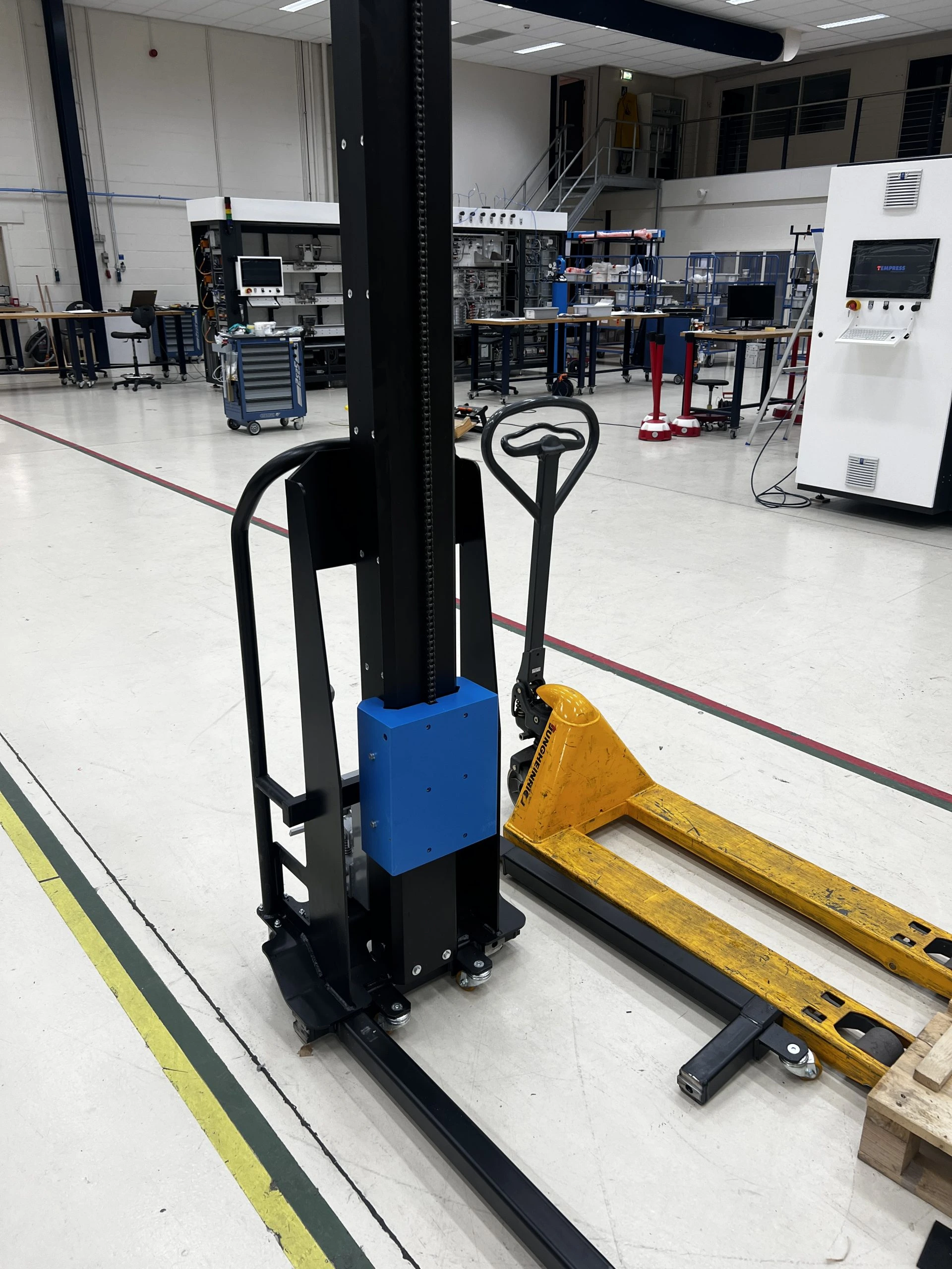 Black mast lift with blue section in a warehouse.