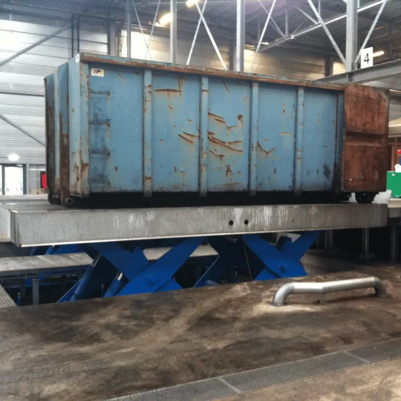 Dock Scissor Lift with large container on top of it in an open warehouse.