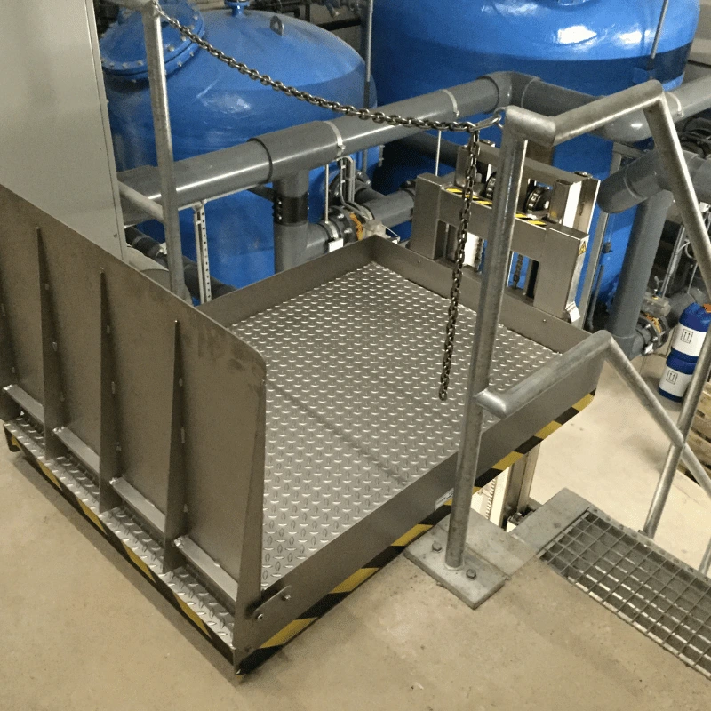 Stainless steel lifting table raised at the top of stairs.